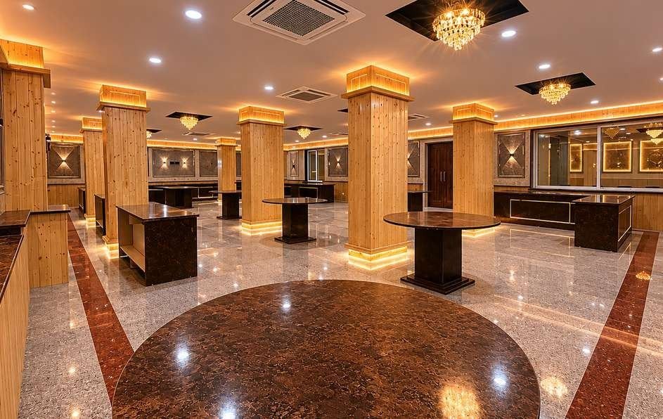 Banquet hall at AIS Residency with pine-clad pillars, cove lighting, crystal chandeliers, buffet counters and a granite floor with an inlaid circle
