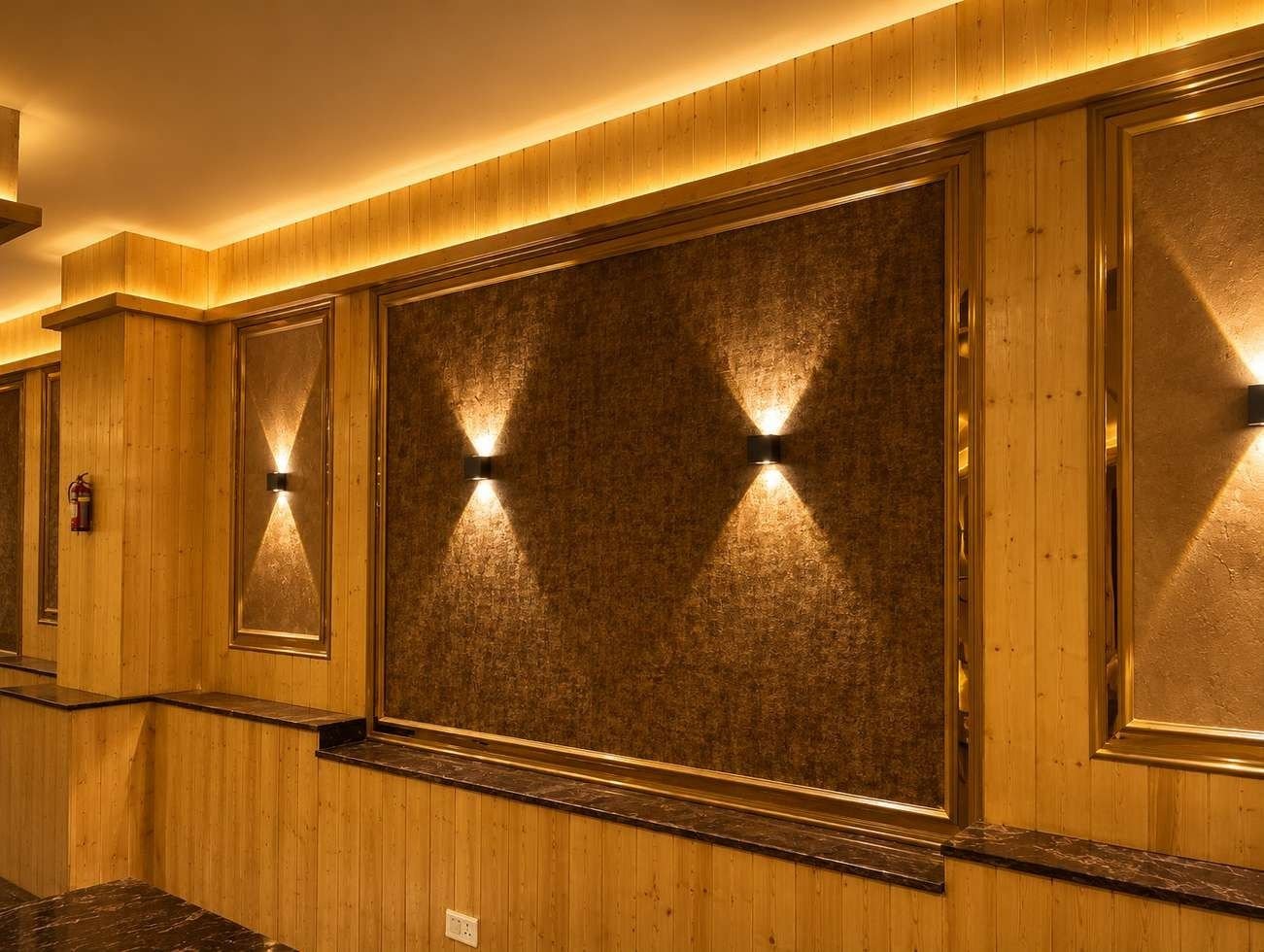 Feature wall in the AIS Residency banquet hall with textured panels, up-and-down wall lights and pine cladding