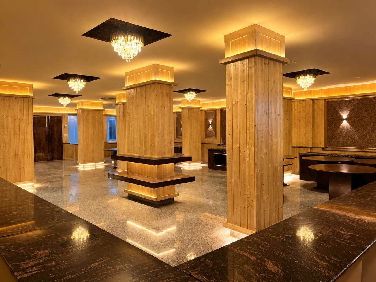 Wide view of the AIS Residency banquet hall with clad pillars, dark granite counters and recessed chandeliers