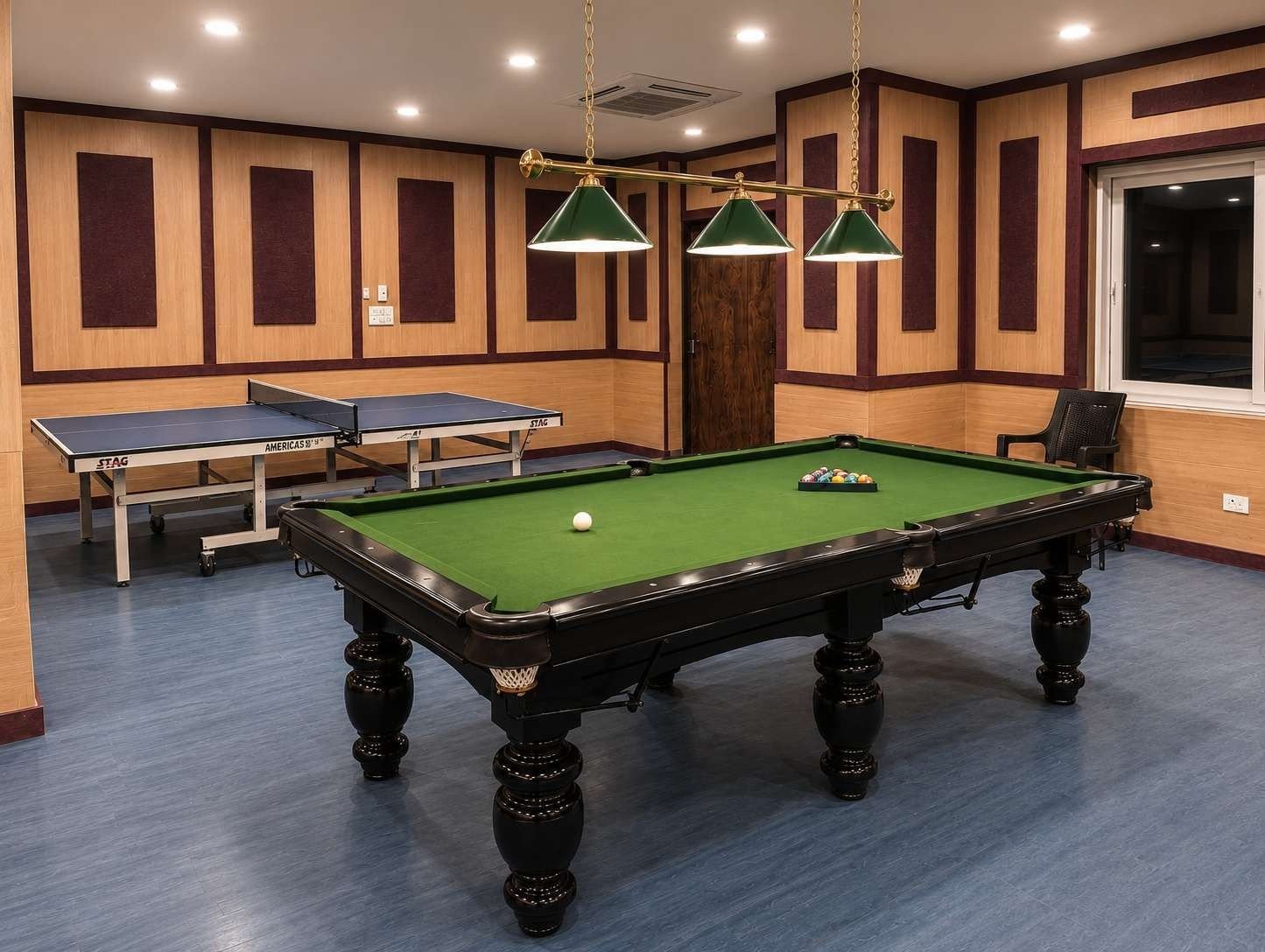 Games zone at AIS Residency with a billiards table under green pendant lamps and table tennis tables behind