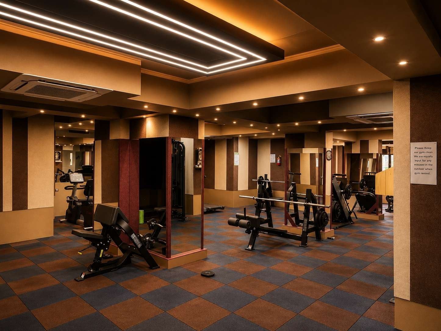 Gymnasium at AIS Residency with strength machines, chequered rubber flooring, striped acoustic wall panels and a lit ceiling feature