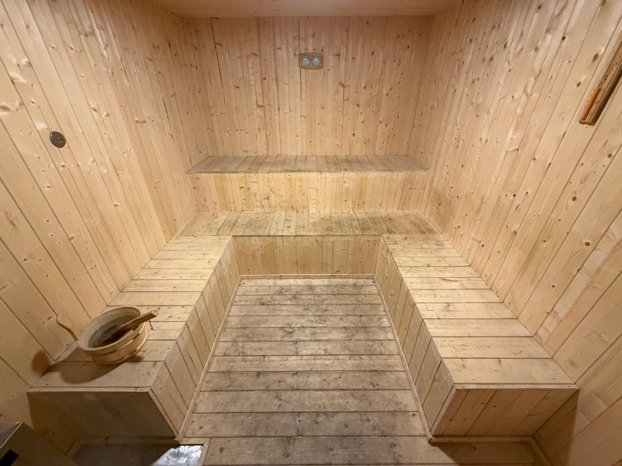 Pine-lined sauna at AIS Residency with U-shaped slatted benches